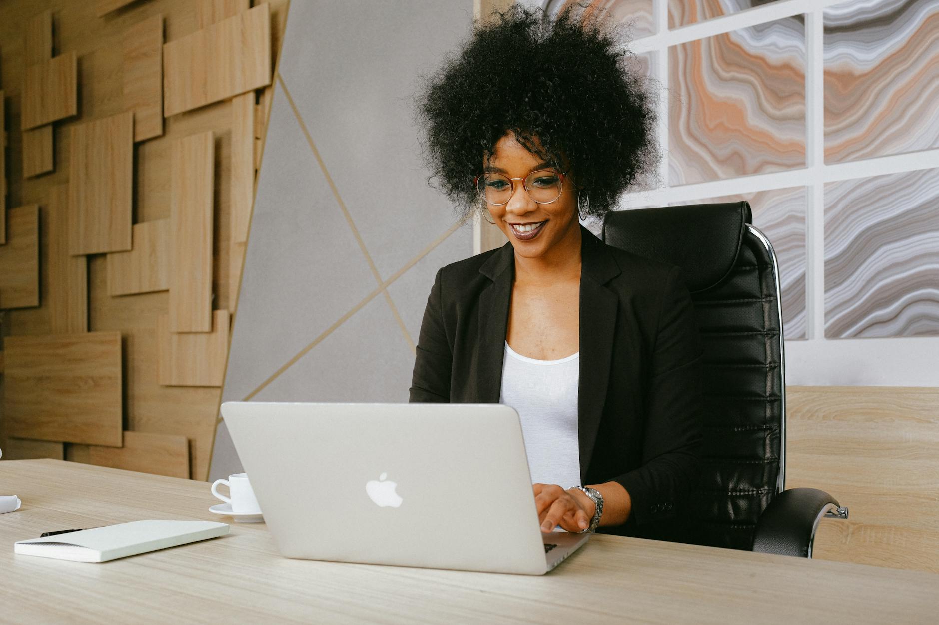 Home 17 woman in black blazer sitting by the table while using macbook