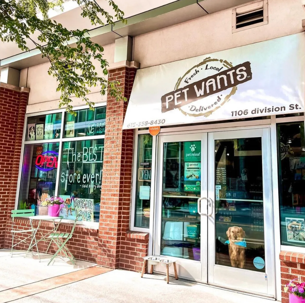 Stylish boutique storefront in East Nashville, colorful vintage display, boho-chic fashion and home décor, unique signage, creative window styling, artistic vibe, sunny day, lifestyle travel photography